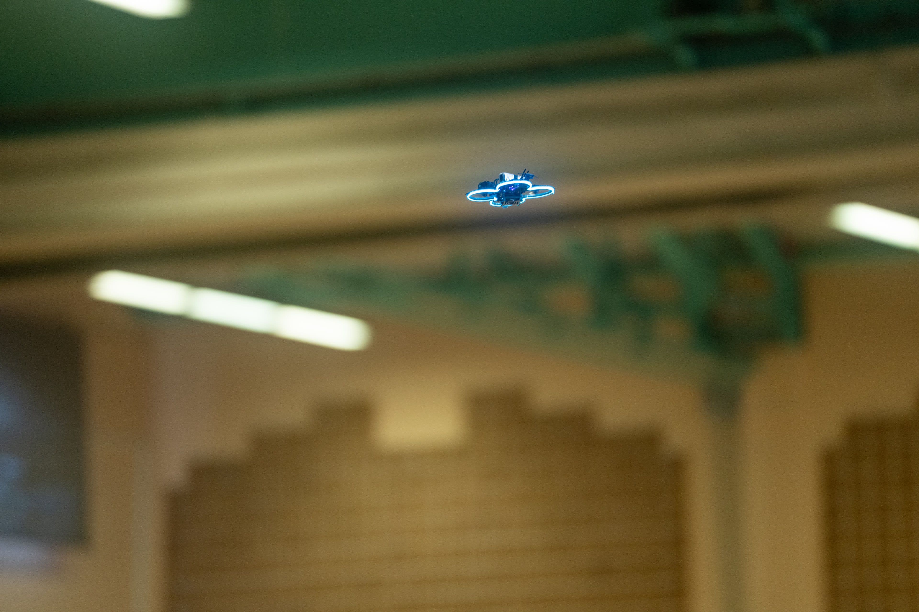 Die Drohne fliegt unter der Hallendecke zwischen den Stahlträgern hindurch