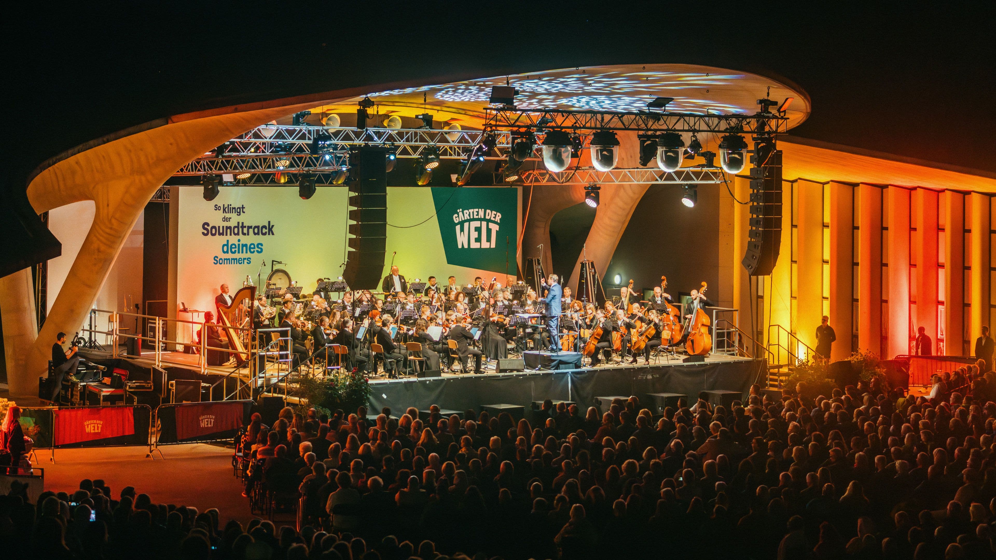 Das Orchester auf der Bühne, davor das Publikum in den ersten Reihen