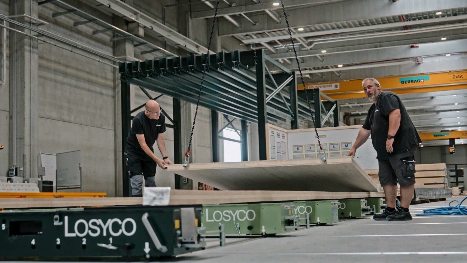 Zwei Mitarbeiter setzen ein Holzelement auf den Transportwagen
