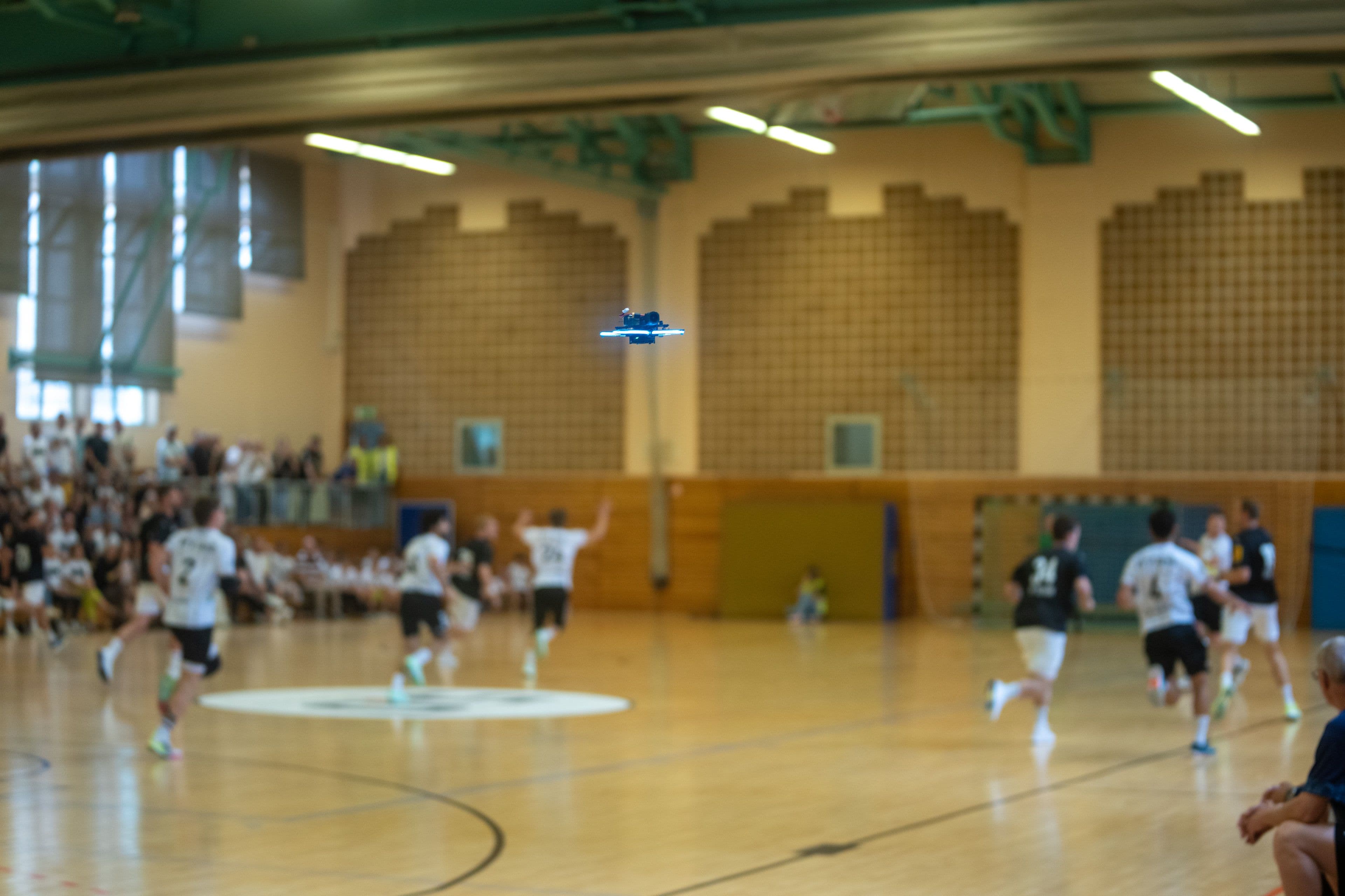 Handballspieler laufen einen Angriff, die Drohne folgt über der Mittellinie